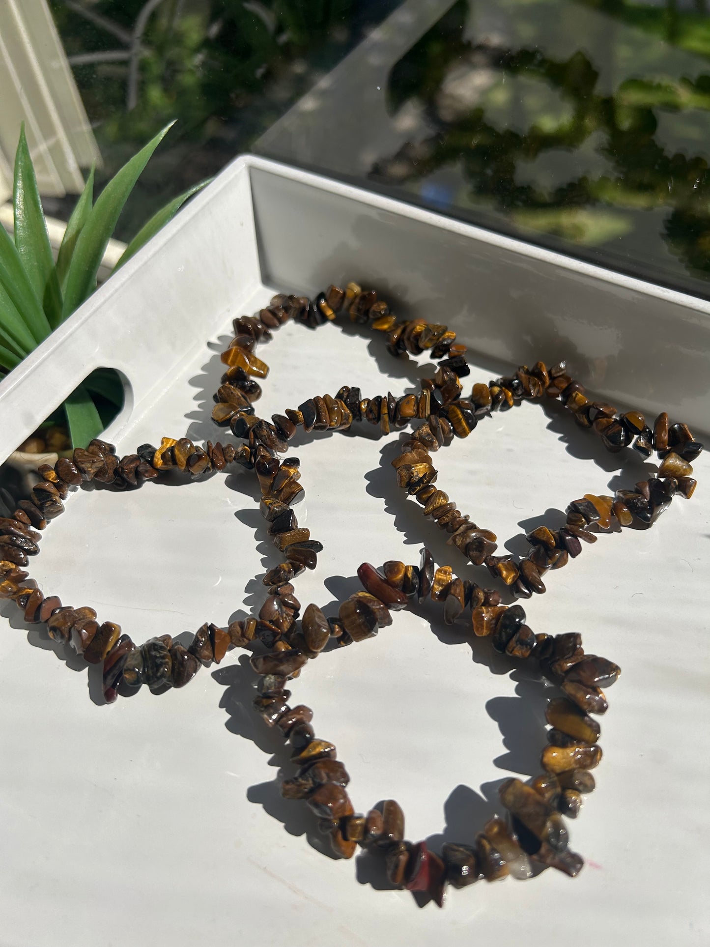 Necklace made of brown stones on a white surface with greenery in the background
