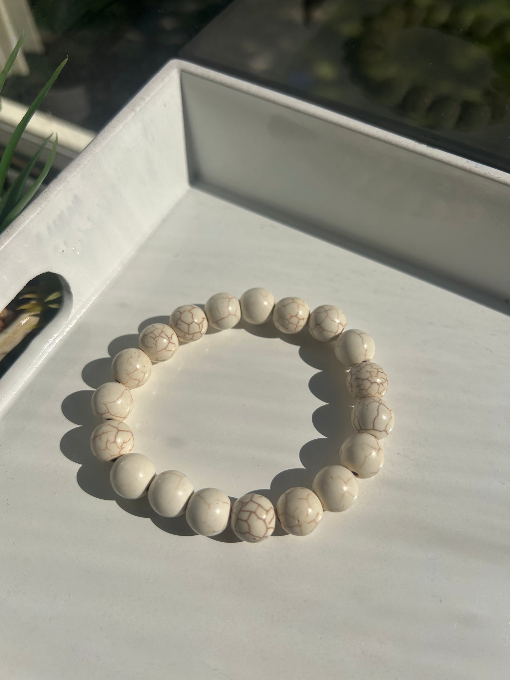 White beaded bracelet on a white surface with a blurred background