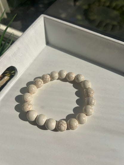 White beaded bracelet on a white surface with a blurred background
