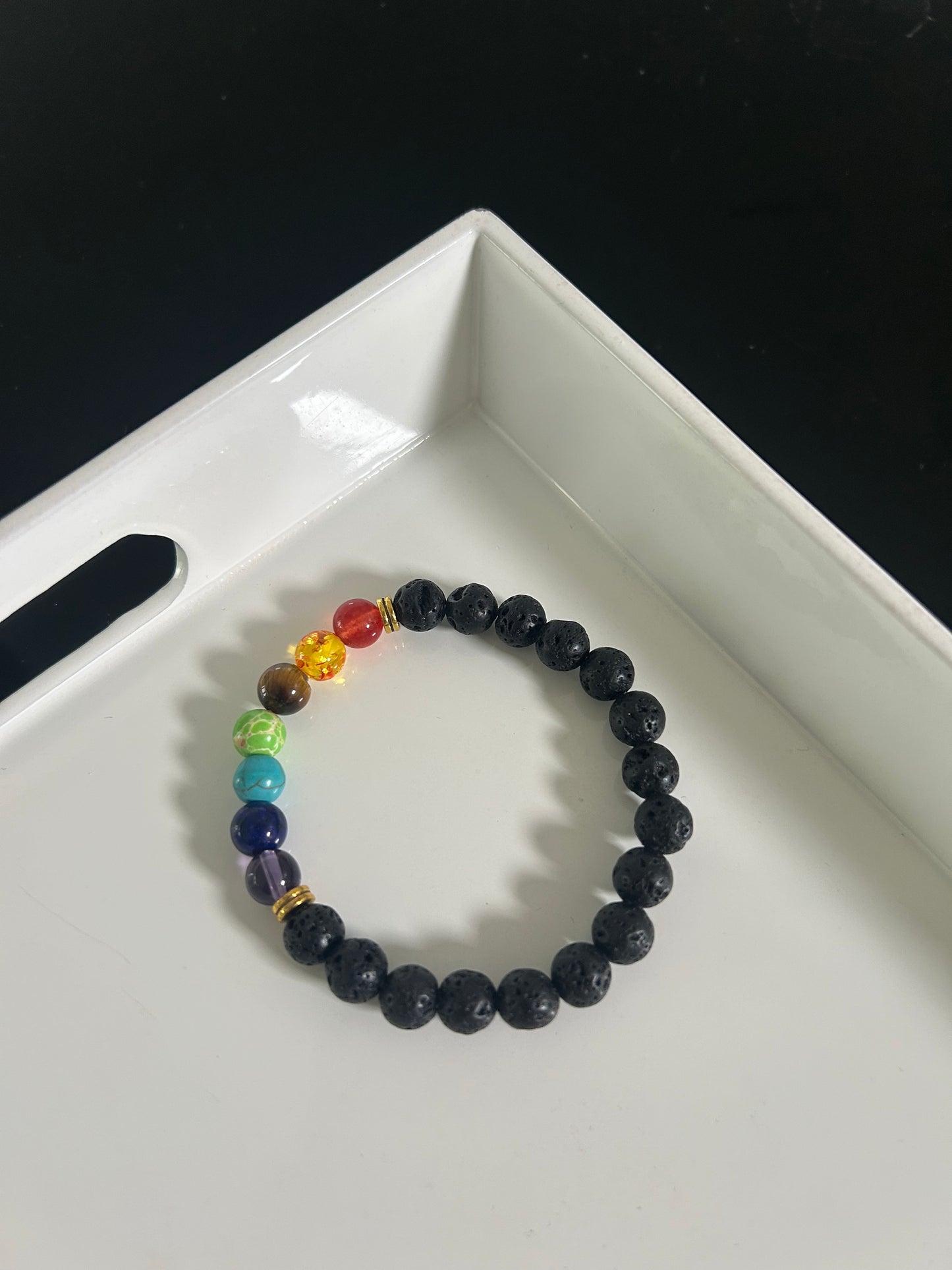 Black beaded bracelet with rainbow-colored beads on a white tray