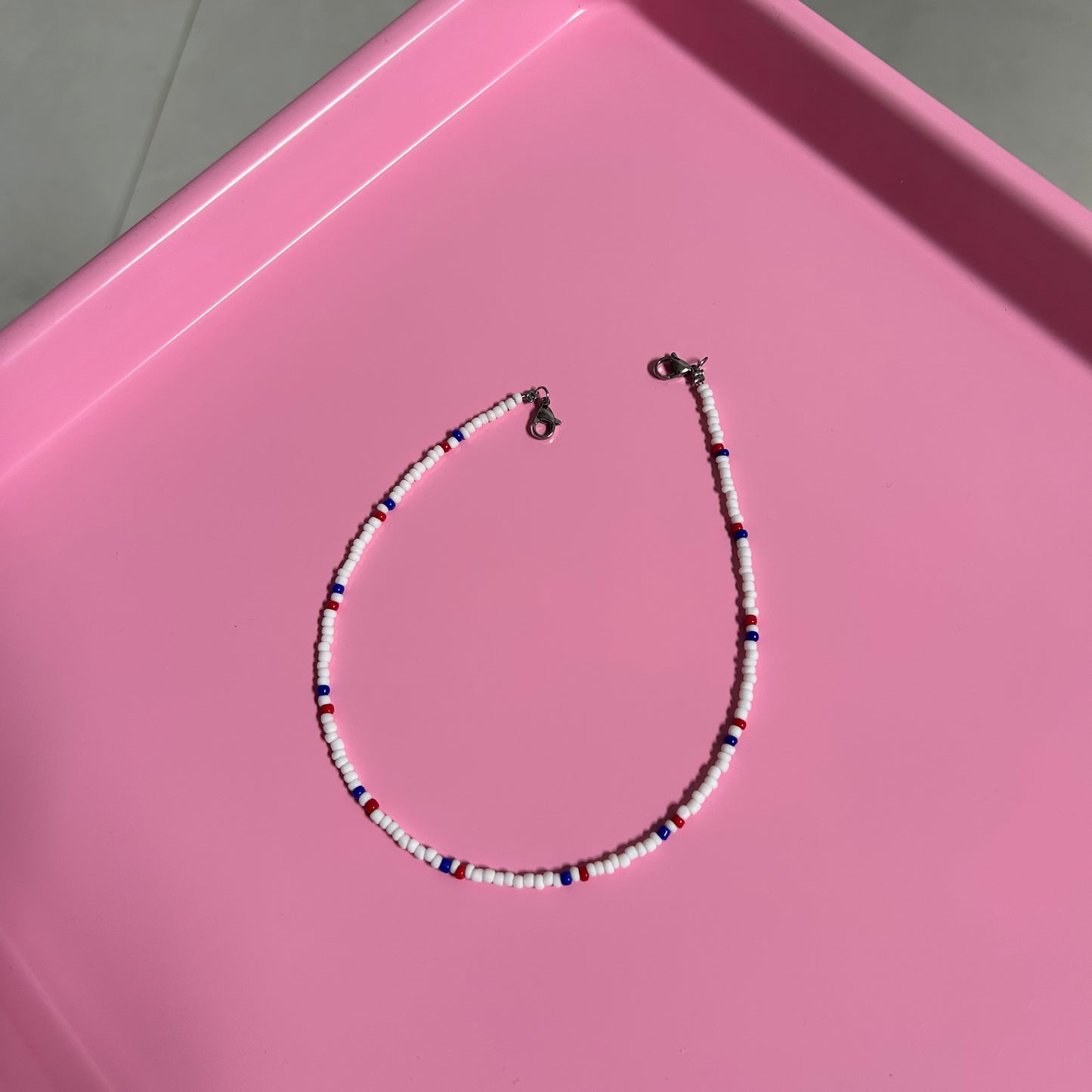Beaded necklace on a pink surface