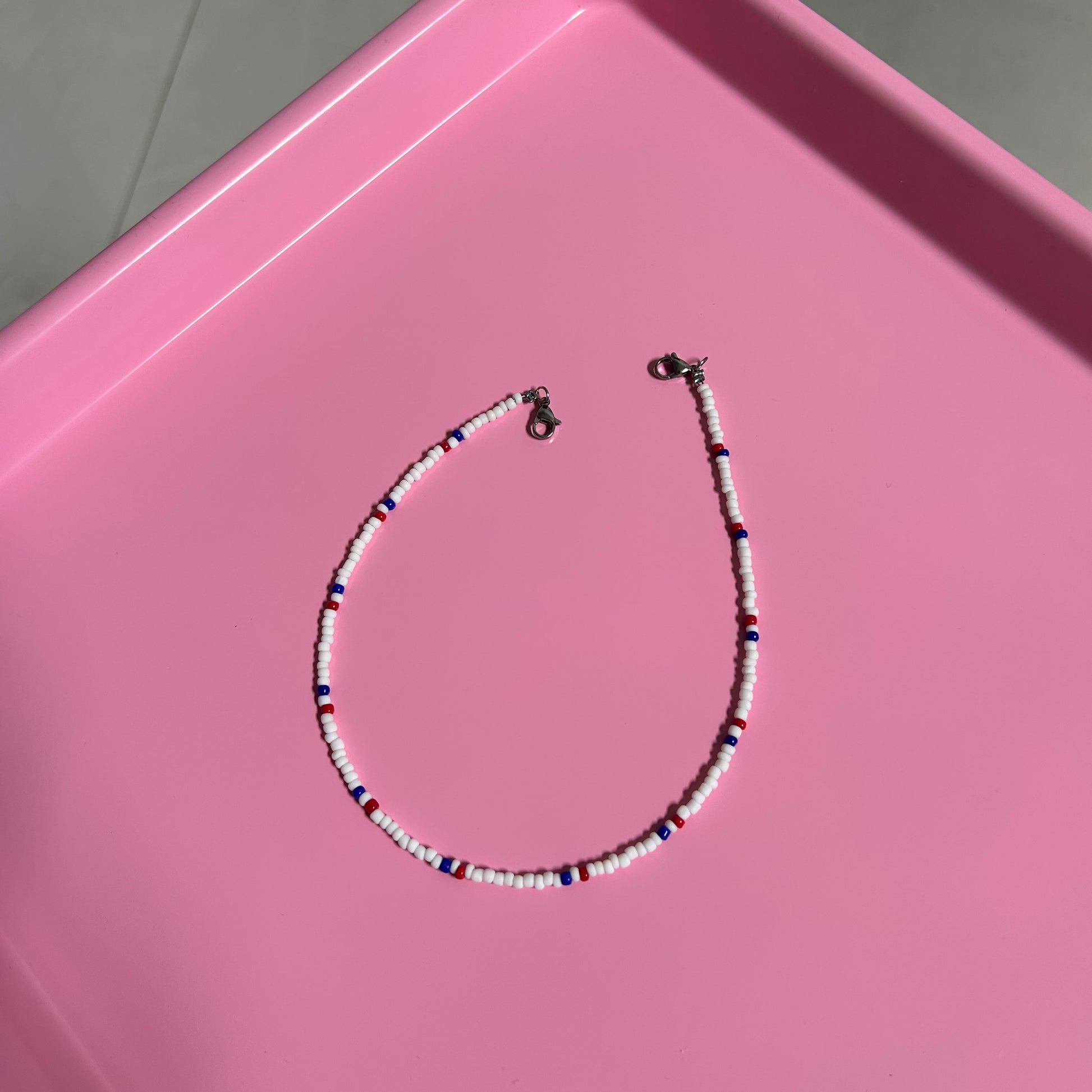 Beaded necklace on a pink surface