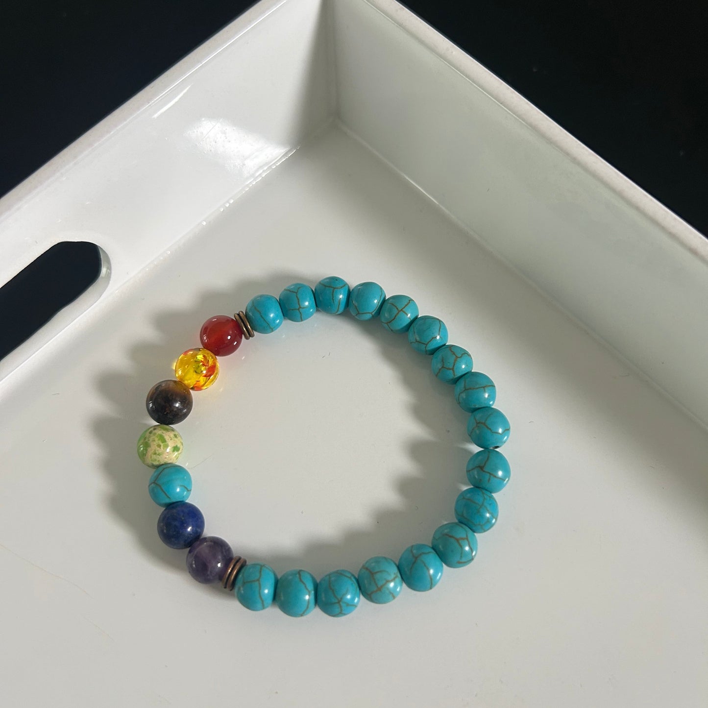 Turquoise beaded bracelet with multicolored beads on a white surface