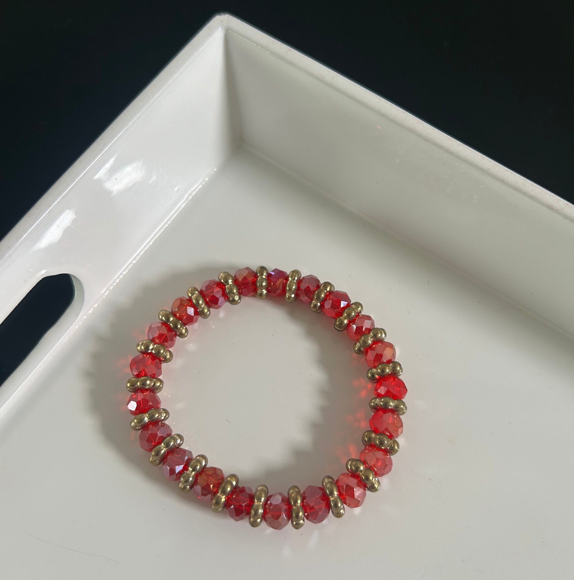 Red beaded bracelet on a white dish with a black background