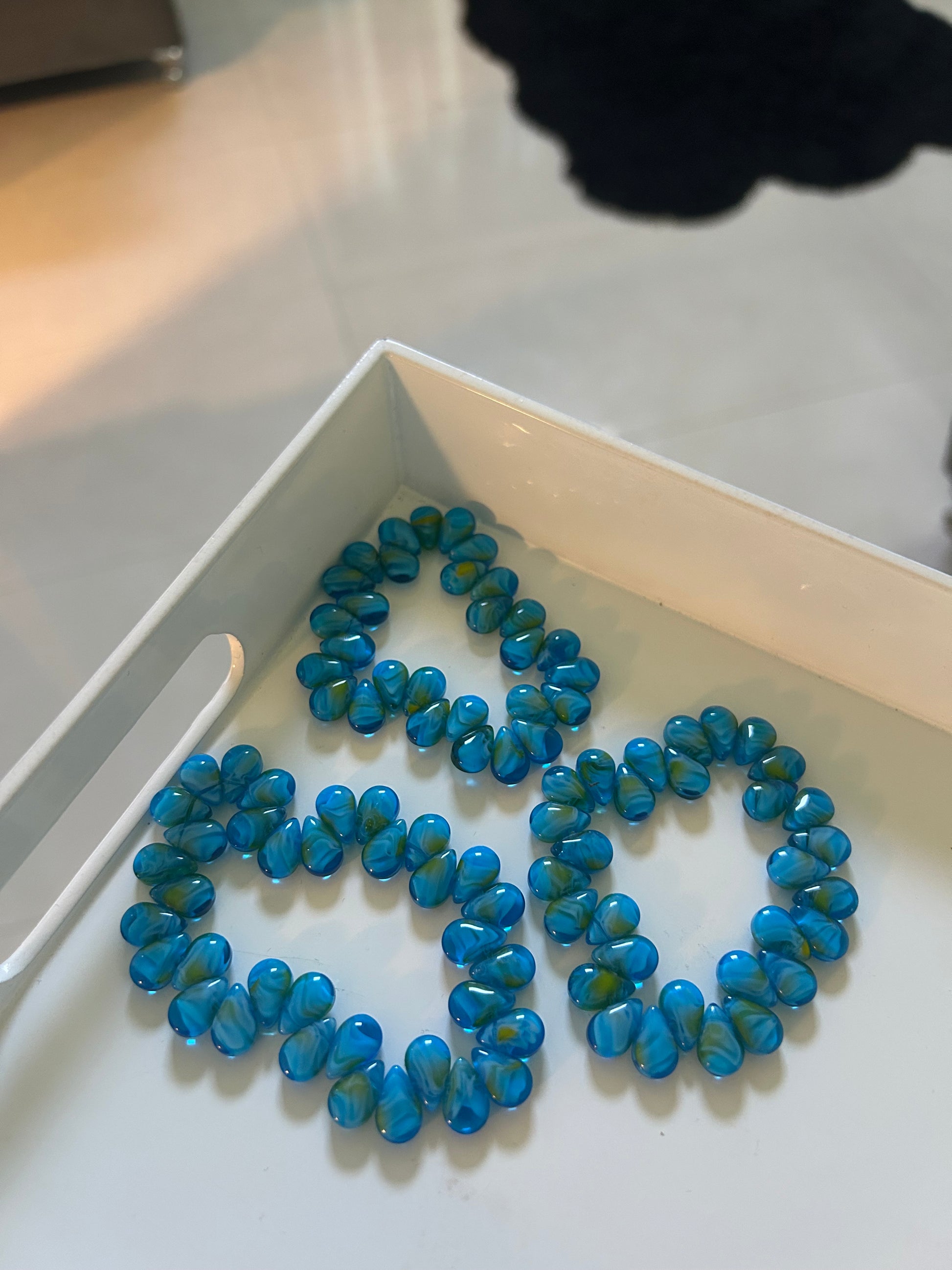 Blue beaded necklace on a white surface