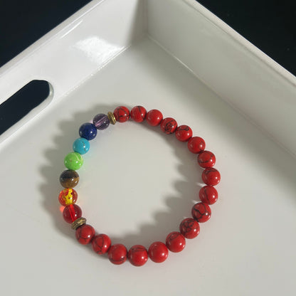 Bracelet with red beads chakra and colorful rainbow beads on a white tray