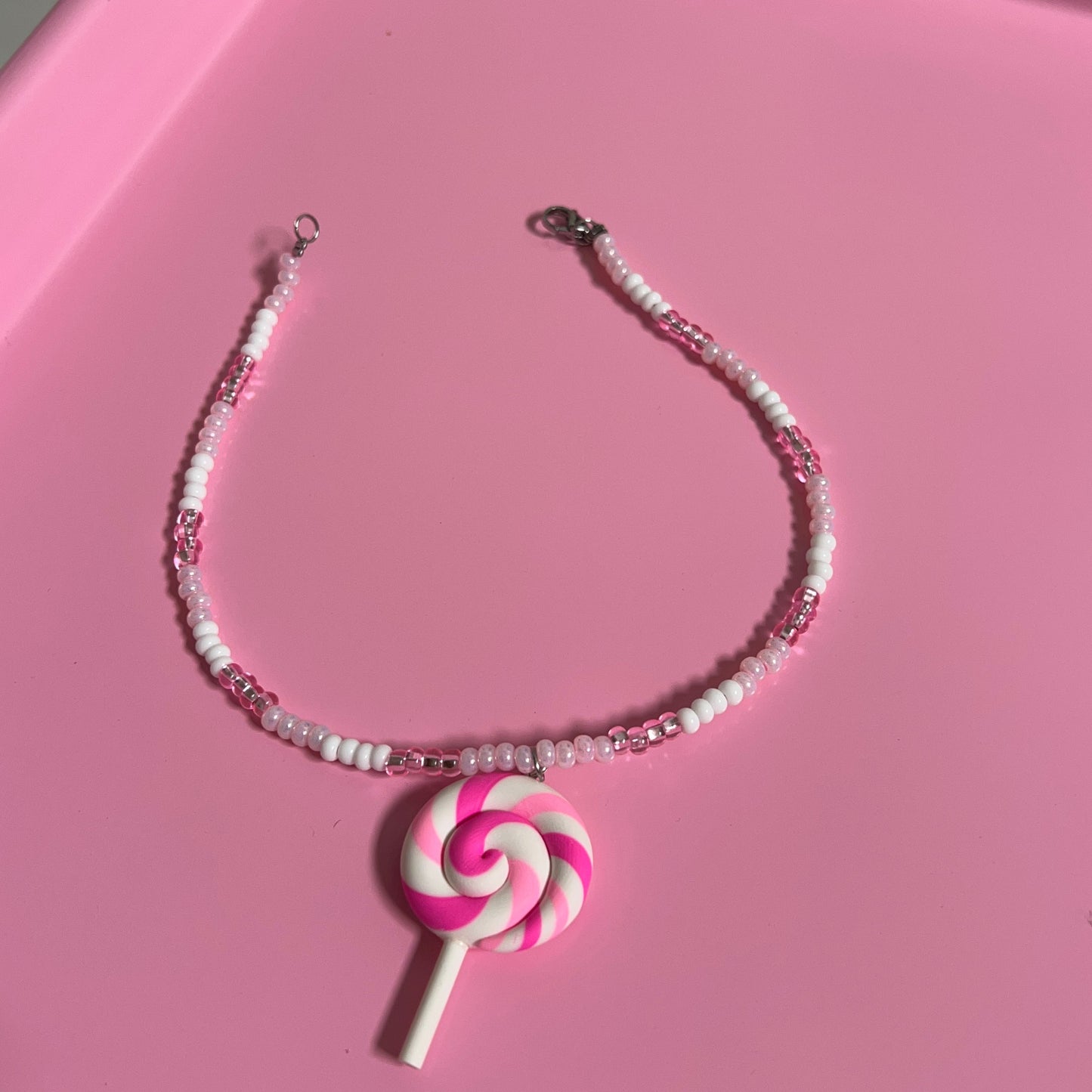 Lollipop-shaped phone strap on a pink surface
