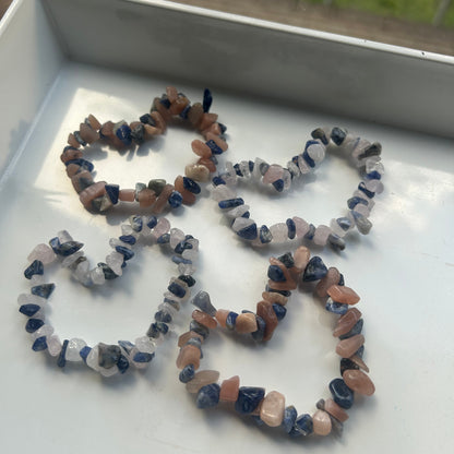 Three small beaded bracelets on a white surface with a blurred outdoor background