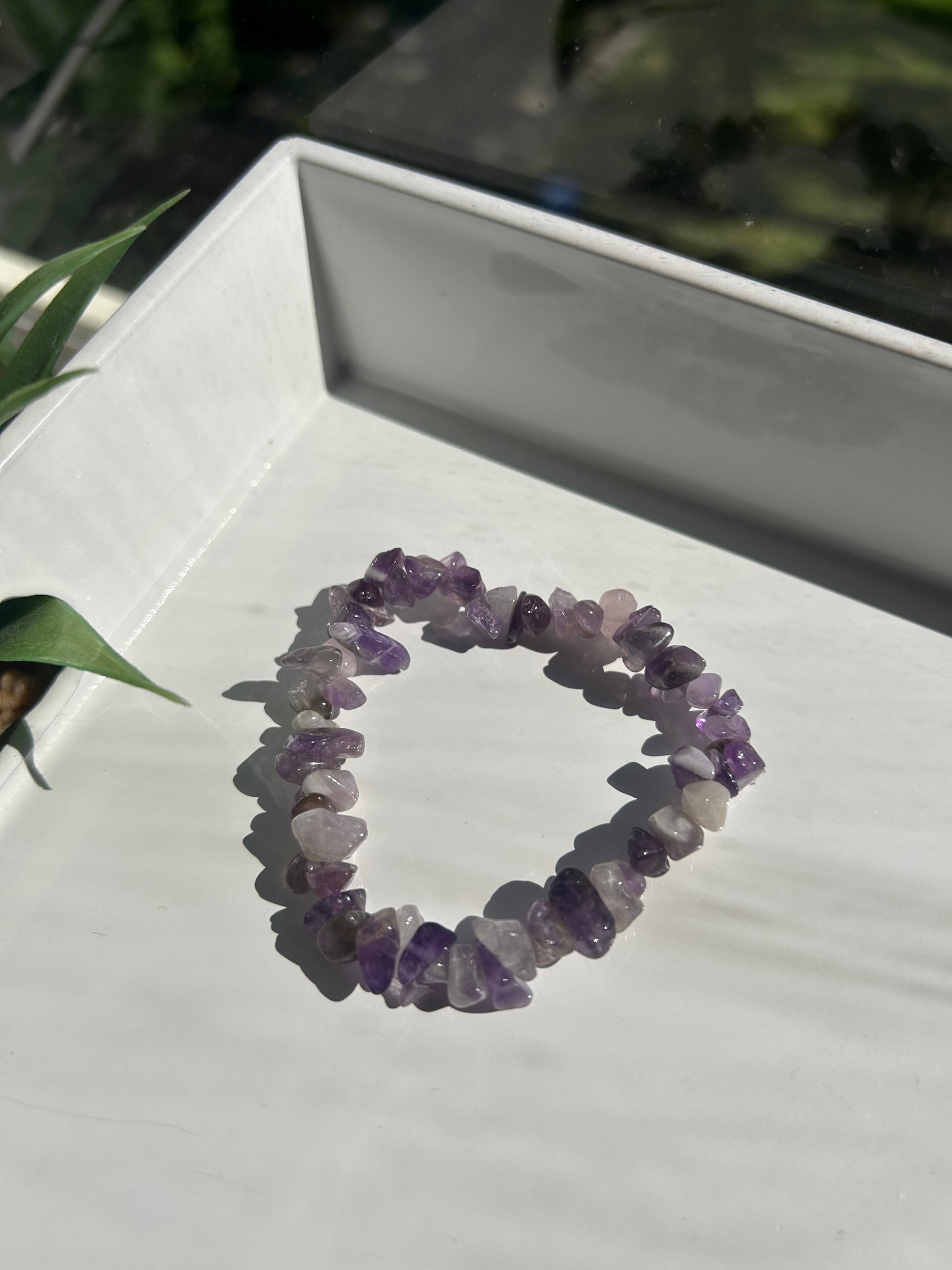 Amethyst chip bracelet on a white surface with a blurred background