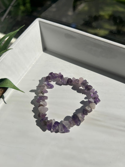 Amethyst chip bracelet on a white surface with a blurred background