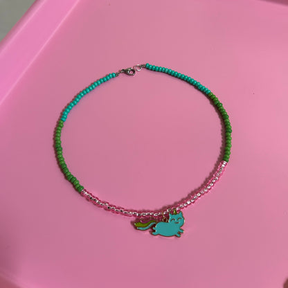 Children Green beaded necklace with a charm on a pink surface