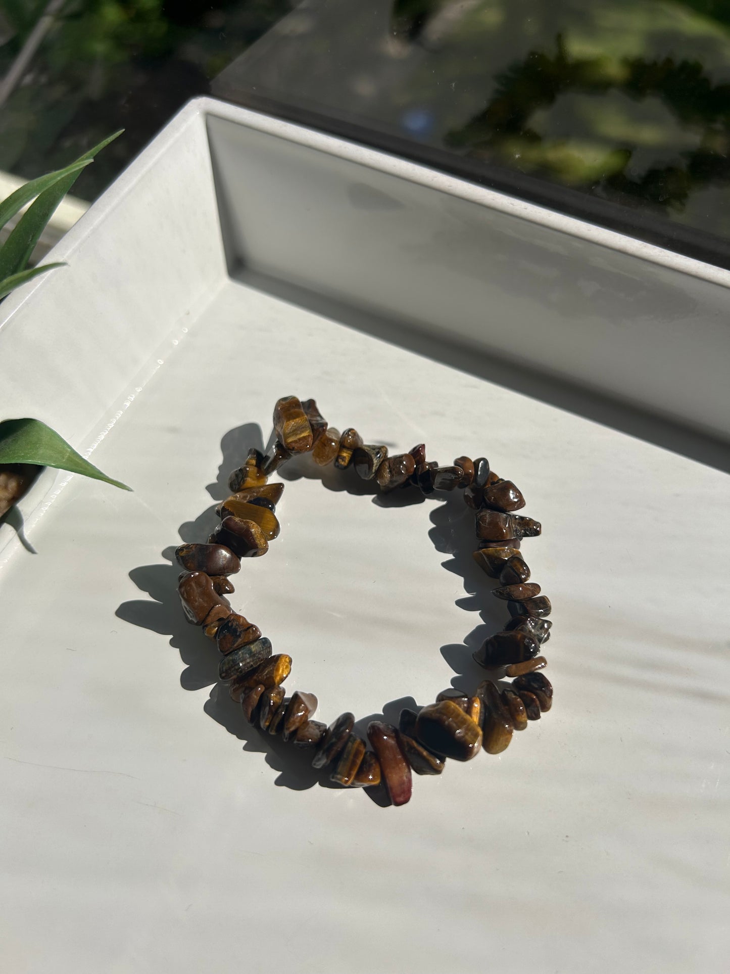 Tiger's eye chip bracelet on a white surface with a blurred background