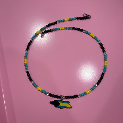 Necklace with colorful beads and a map charm on a pink surface