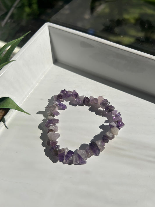 Amethyst chip bracelet on a white surface with a blurred background