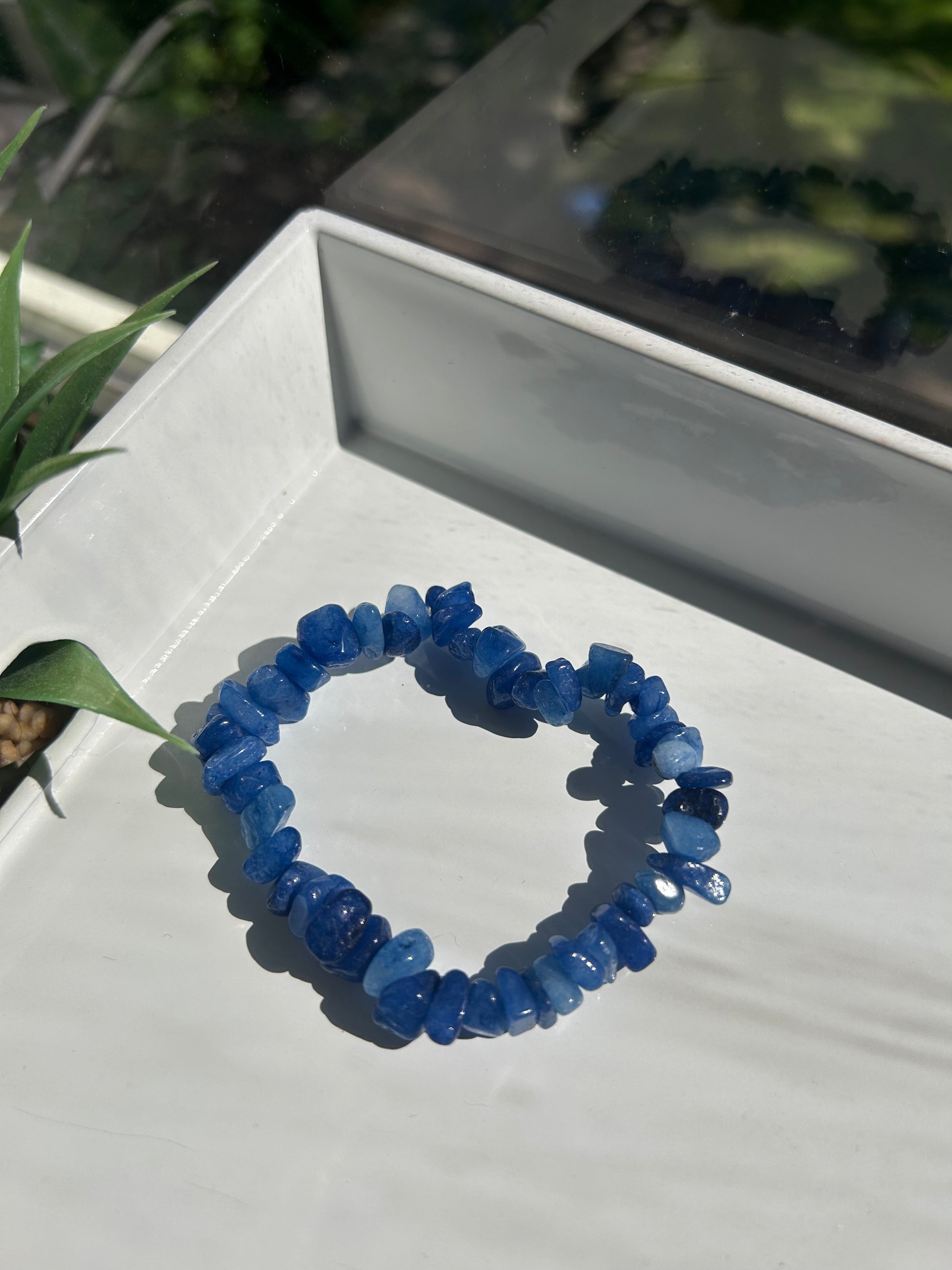 Blue beaded bracelet on a white surface with a blurred background