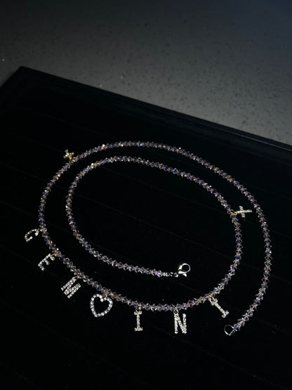Two silver necklaces with engraved letters on a black background