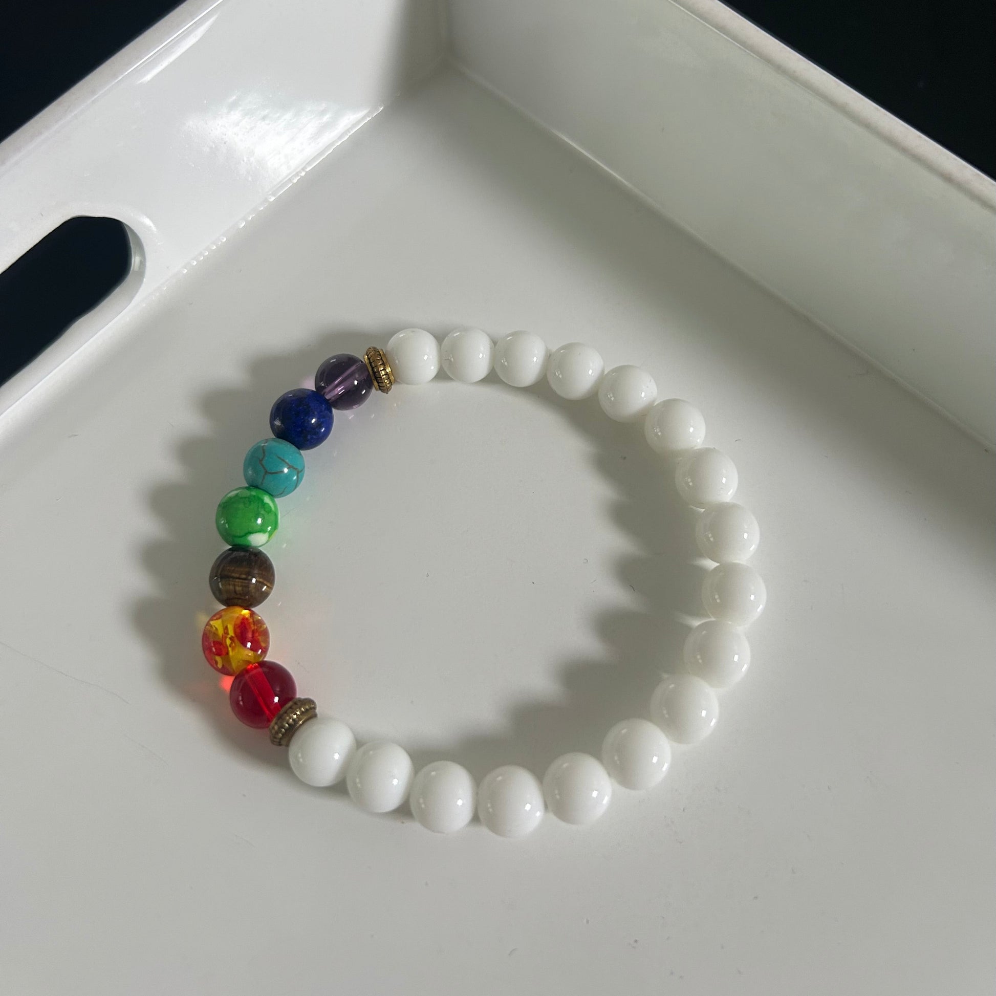 Beaded bracelet with white beads and colorful beads on a white tray
