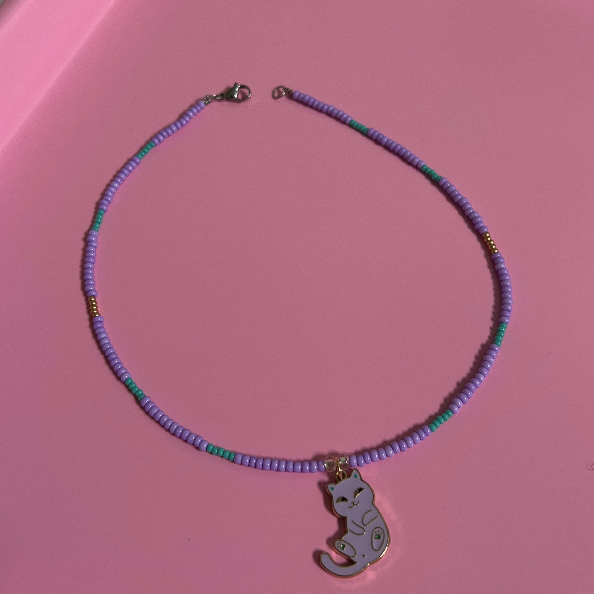 Necklace with a purple beaded necklace and elephant pendant on a pink surface