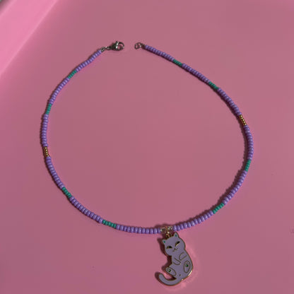 Necklace with a purple beaded necklace and elephant pendant on a pink surface