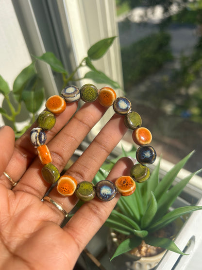 Hand wearing a colorful beaded bracelet with a blurred indoor background