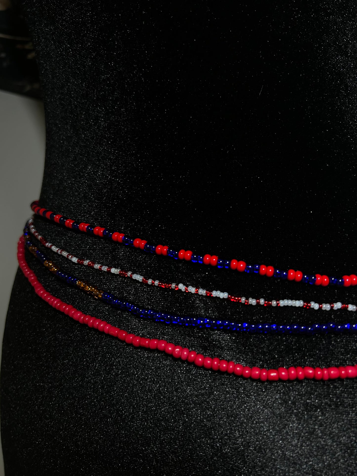 Three beaded necklaces in red, blue, and white on a black background