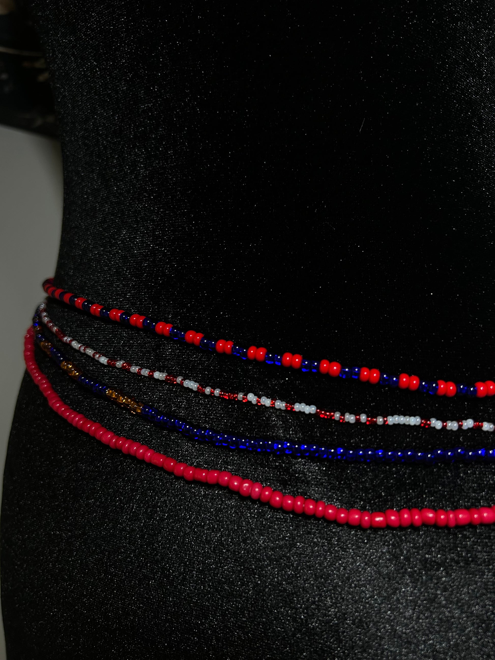 Three beaded necklaces in red, blue, and white on a black background