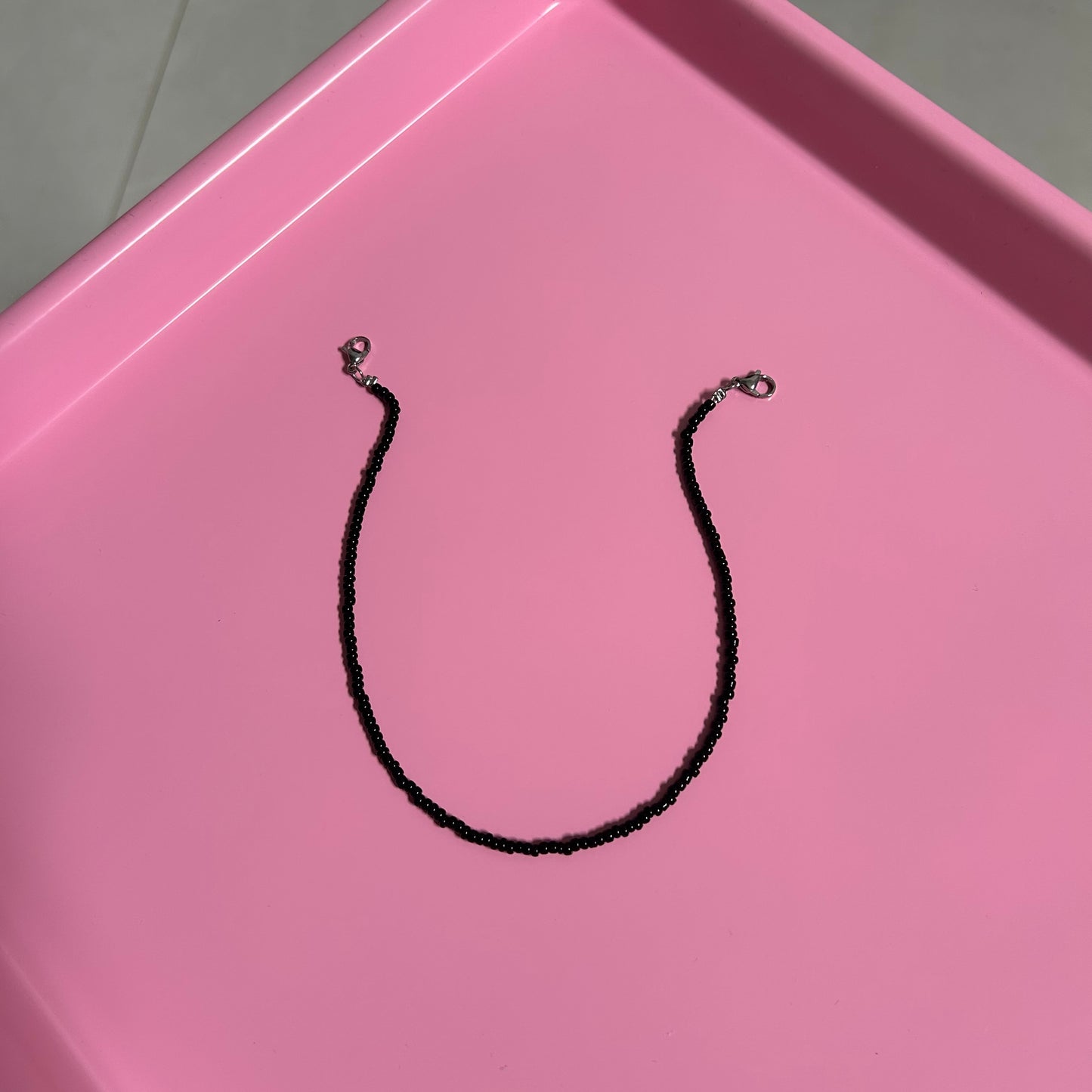 Black necklace on a pink tray