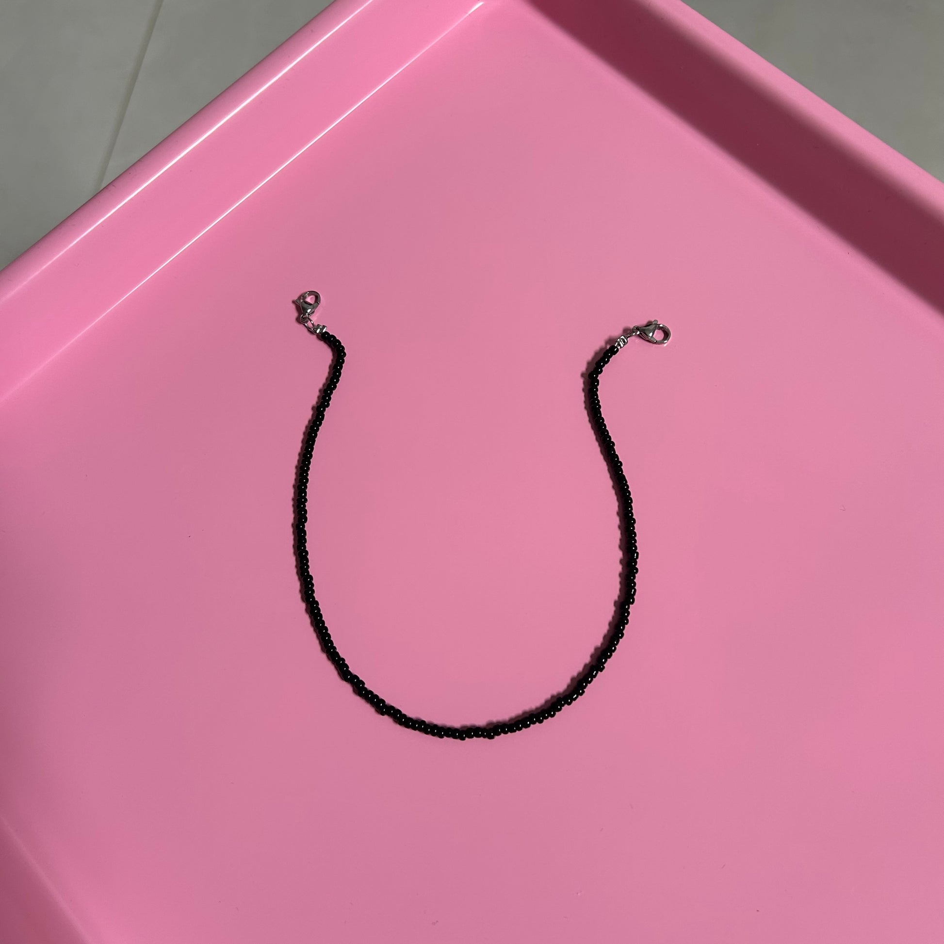 Black necklace on a pink tray