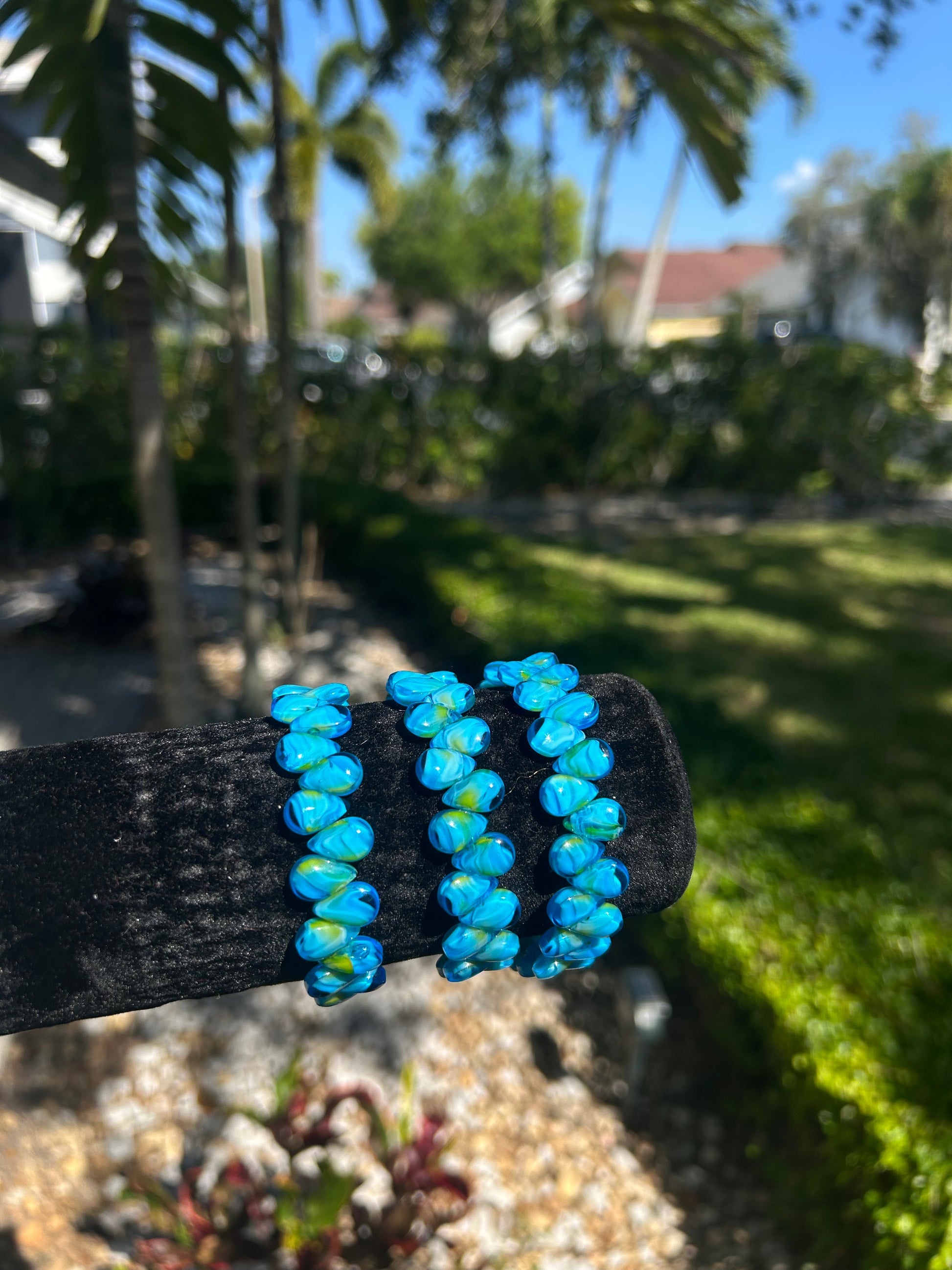 Blue beaded bracelet on a black background with a blurred outdoor setting