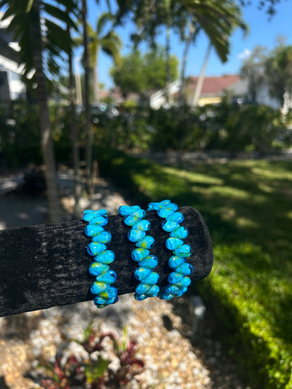 Blue beaded bracelet on a black background with a blurred outdoor setting