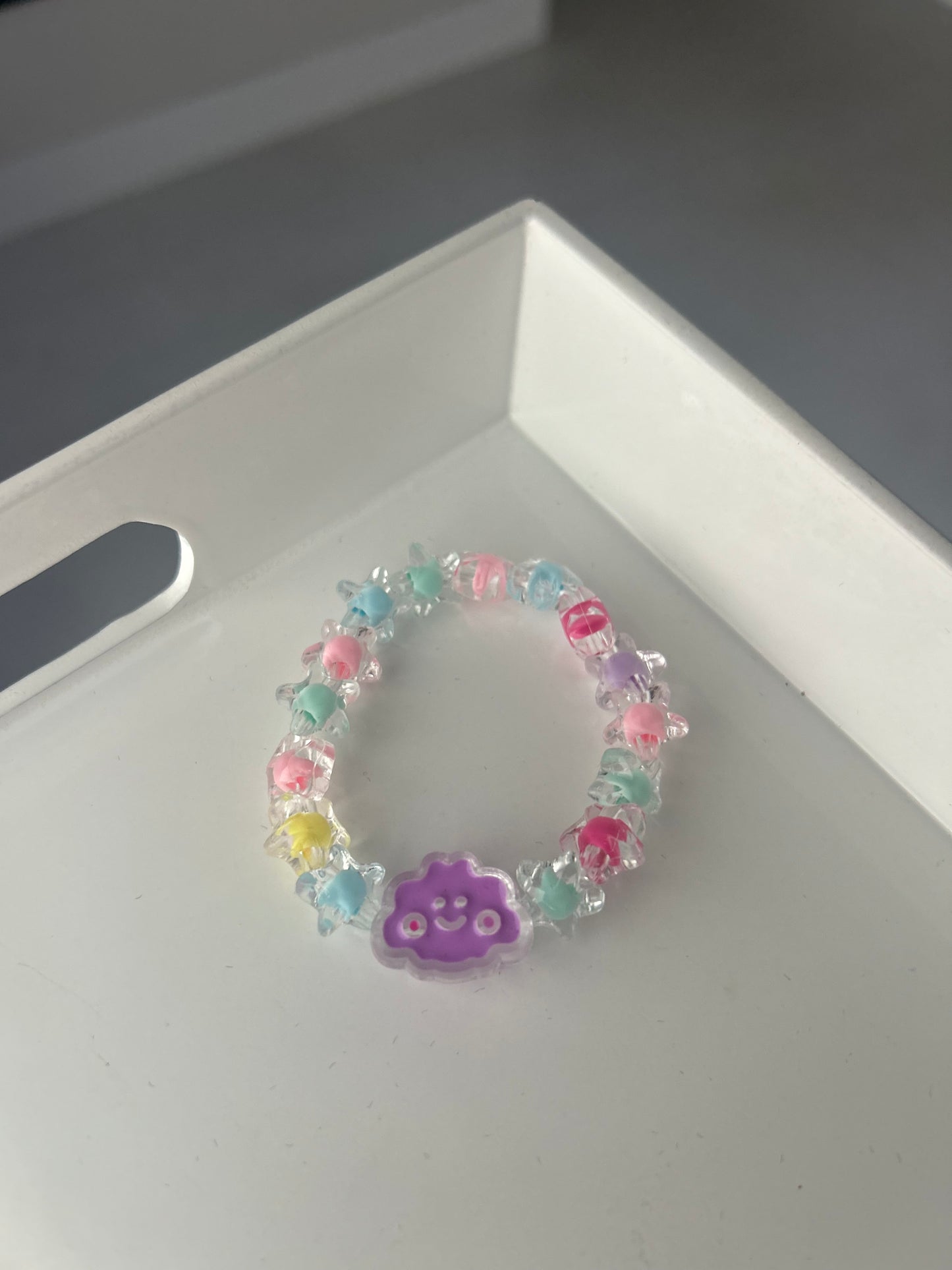 Children Colorful bracelet with a purple heart charm on a white surface