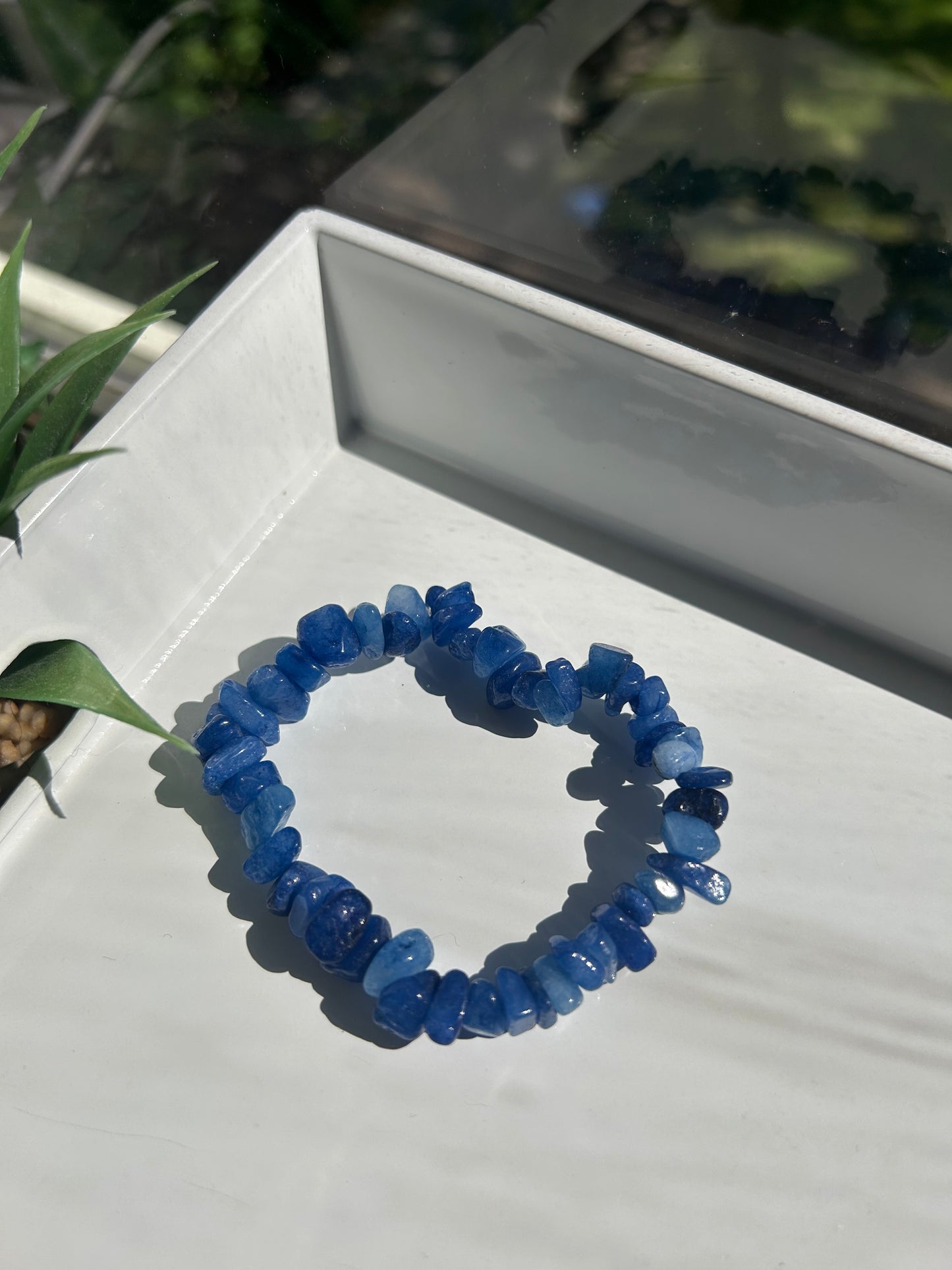 Blue beaded bracelet on a white surface with a blurred background