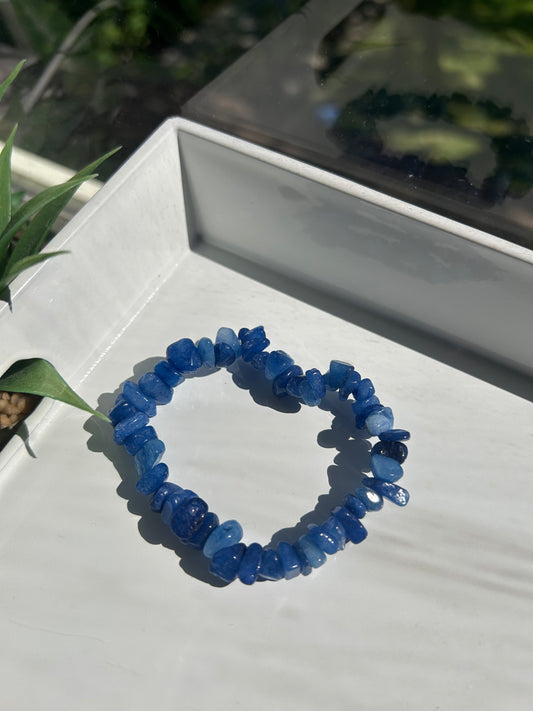 Blue beaded bracelet on a white surface with a blurred background