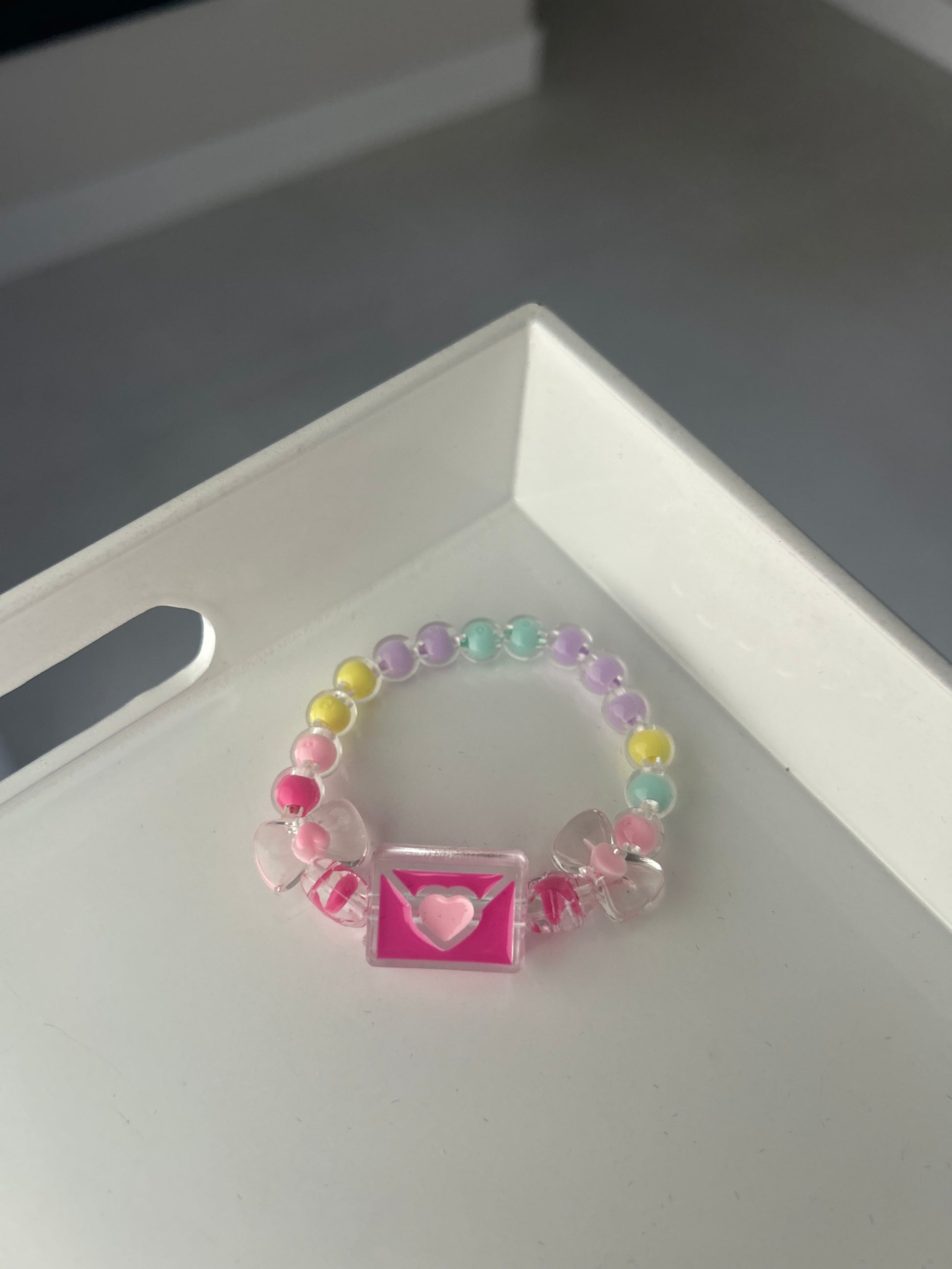 Children Colorful beaded bracelet with a pink heart charm on a white surface