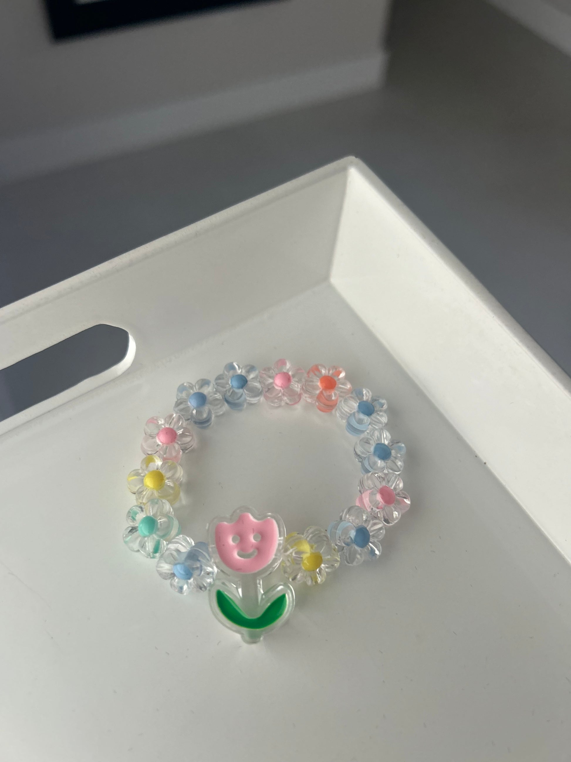 Colorful beaded bracelet with letter 'B' charm on a white surface