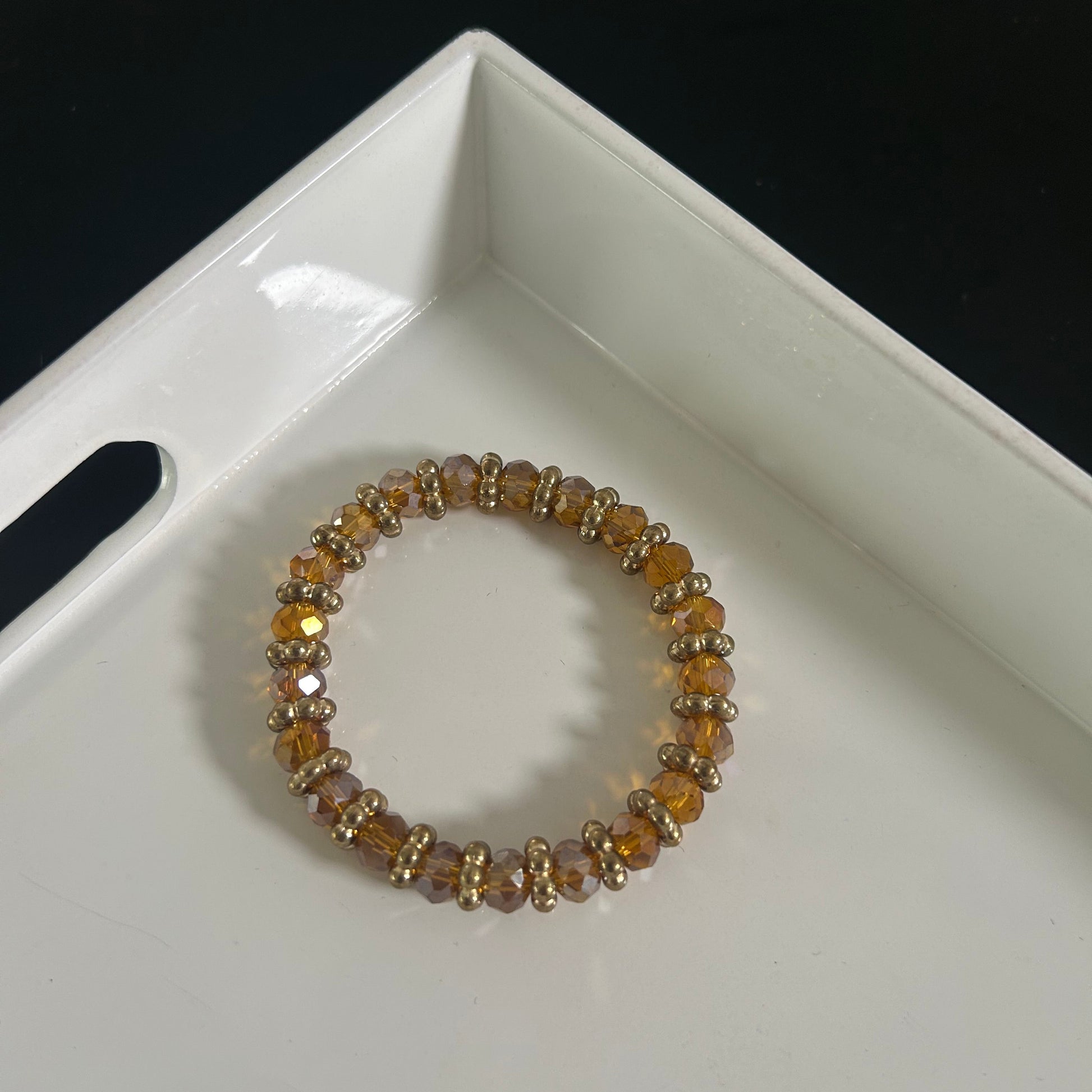 Beaded bracelet on a white tray with a black background