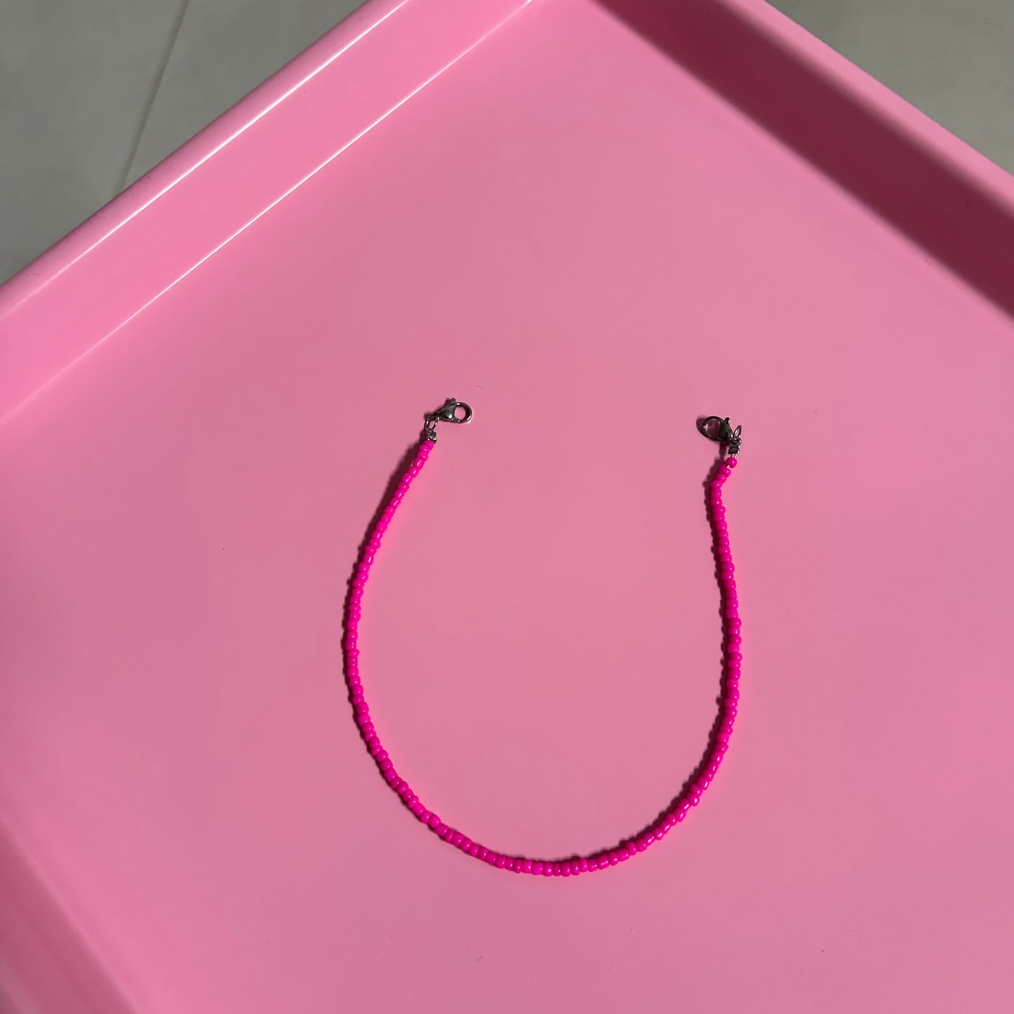 Pink beaded necklace on a pink tray