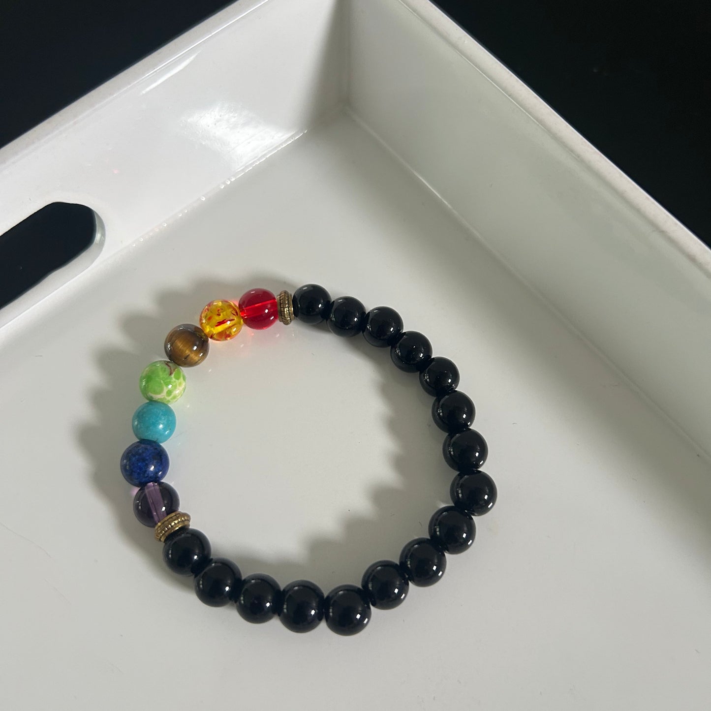 Black chakra beaded bracelet with colorful beads on a white surface