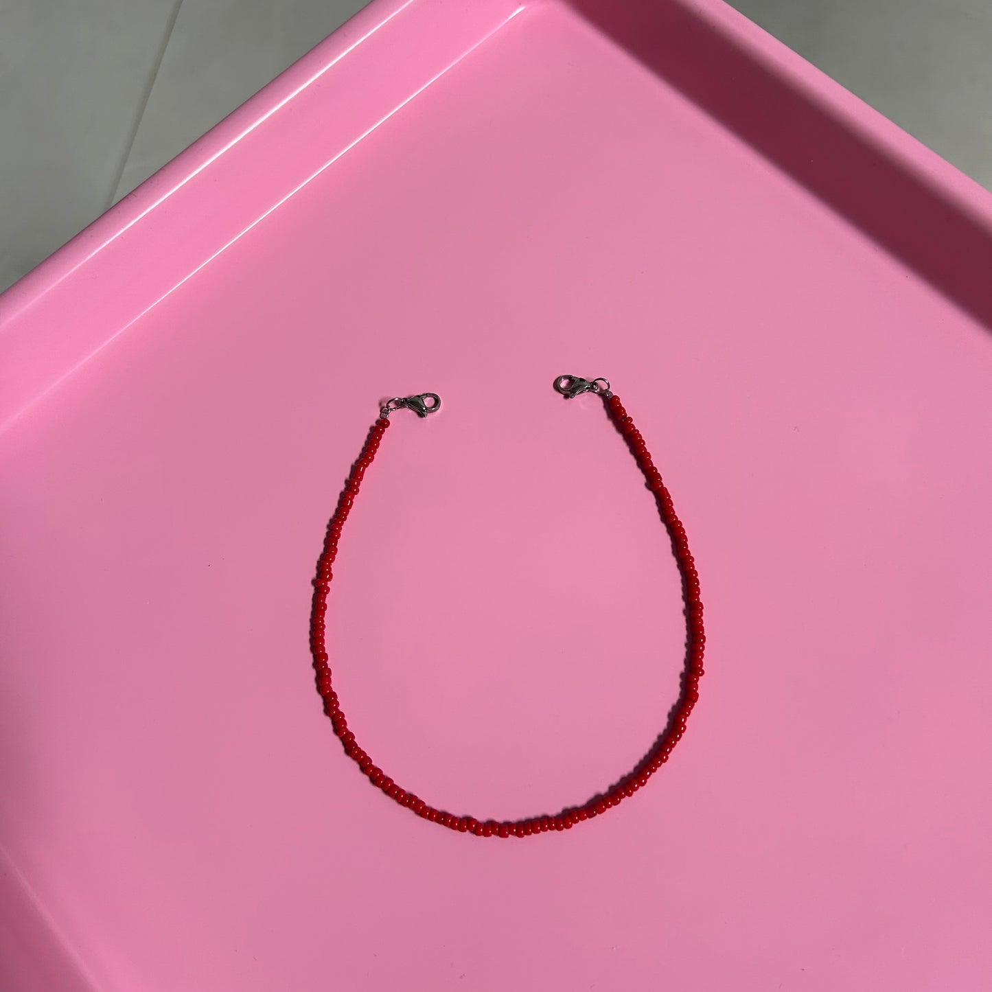 Red beaded necklace on a pink tray