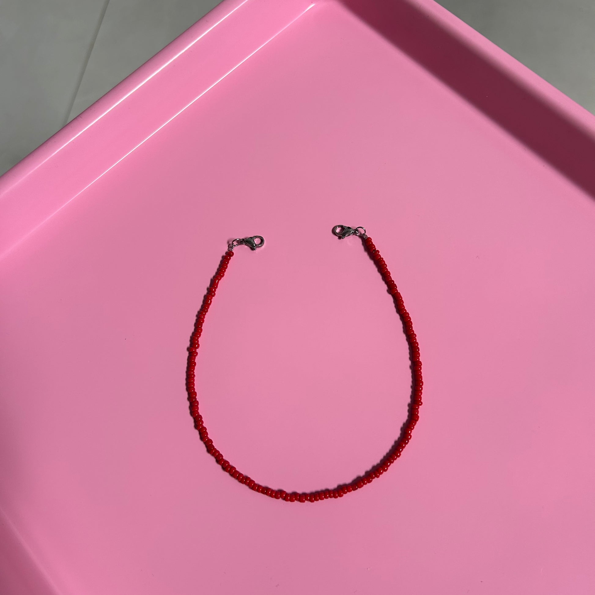 Red beaded necklace on a pink tray
