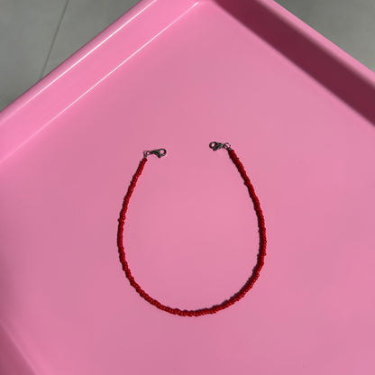 Red beaded necklace on a pink tray