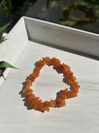 Orange stone bracelet on a white surface with a blurred background