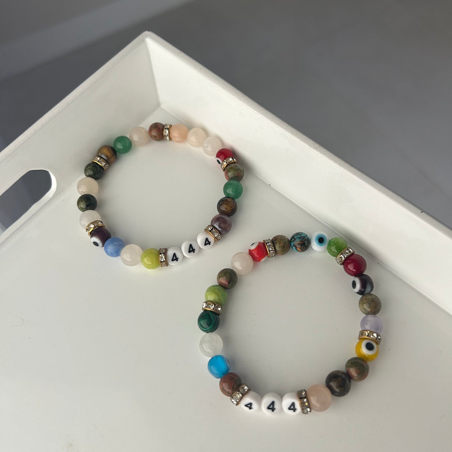 Two beaded bracelets 444 on a white surface with a gray background