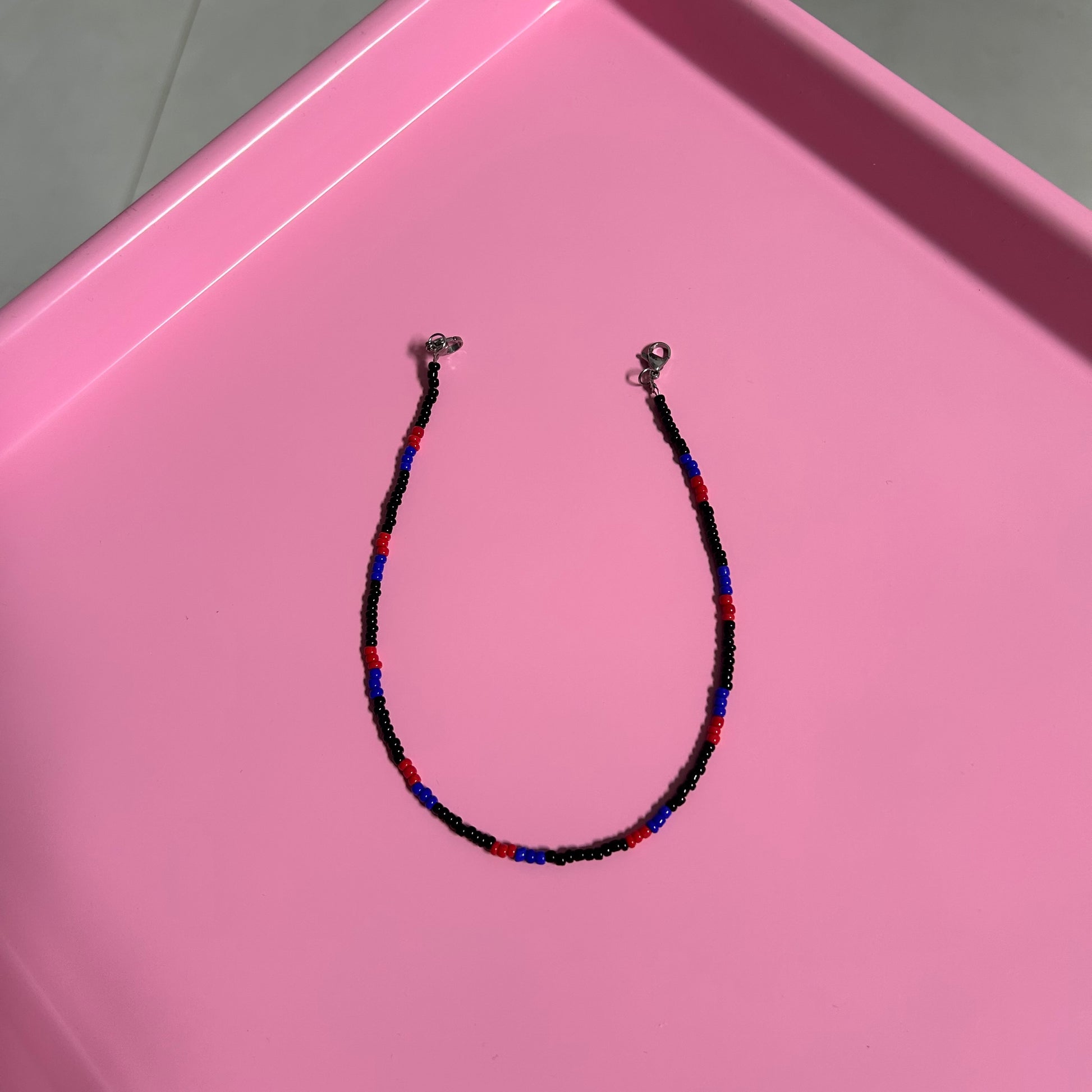 Beaded necklace on a pink surface