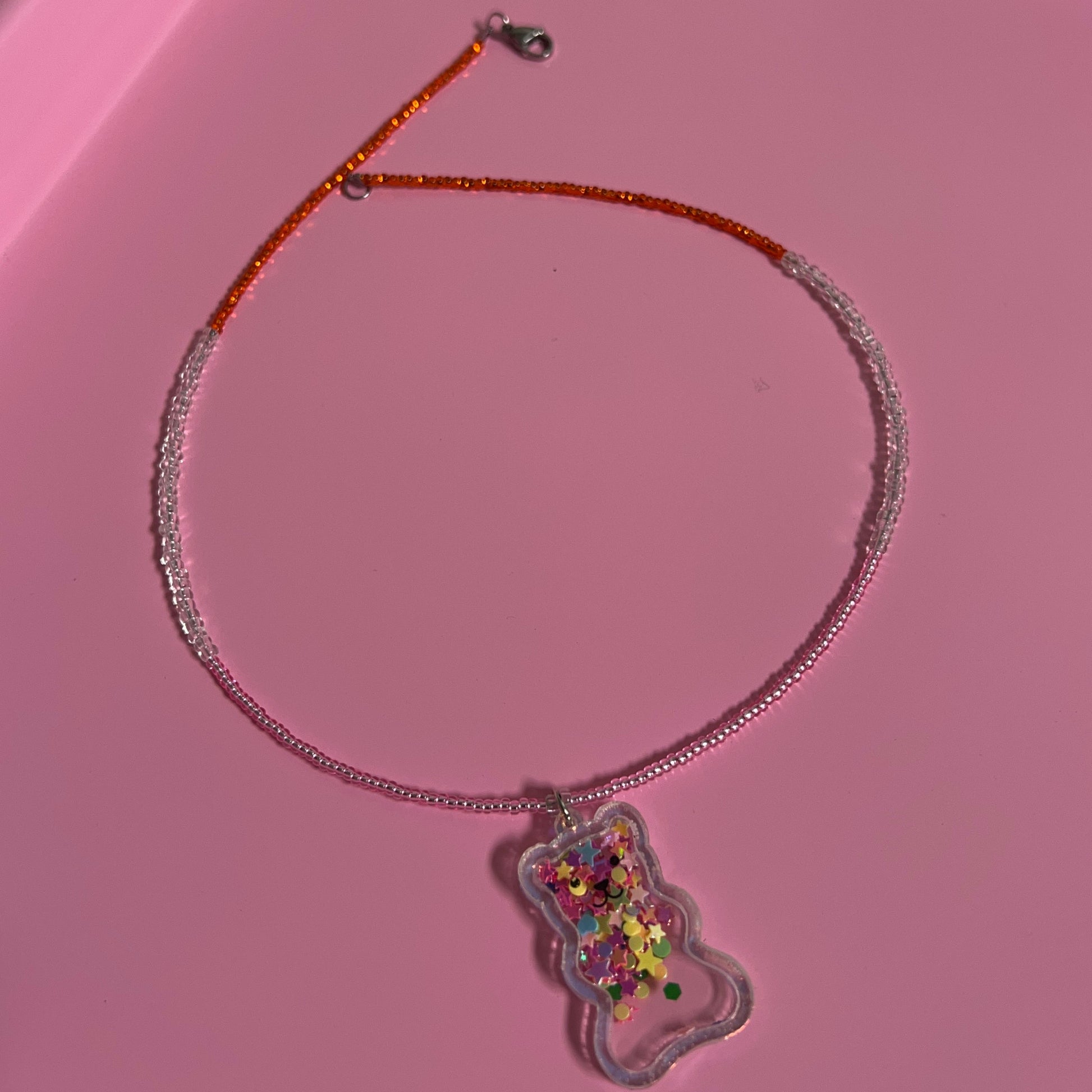 Children Necklace with a colorful charm on a pink surface