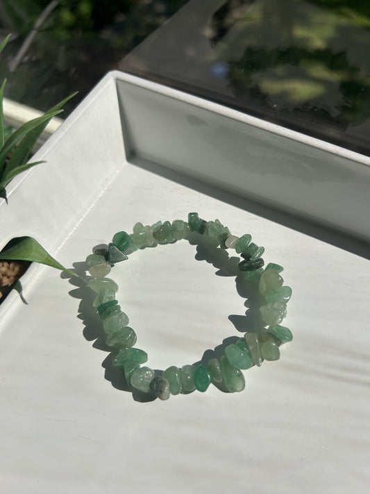 Green stone bracelet on a white surface with a blurred background