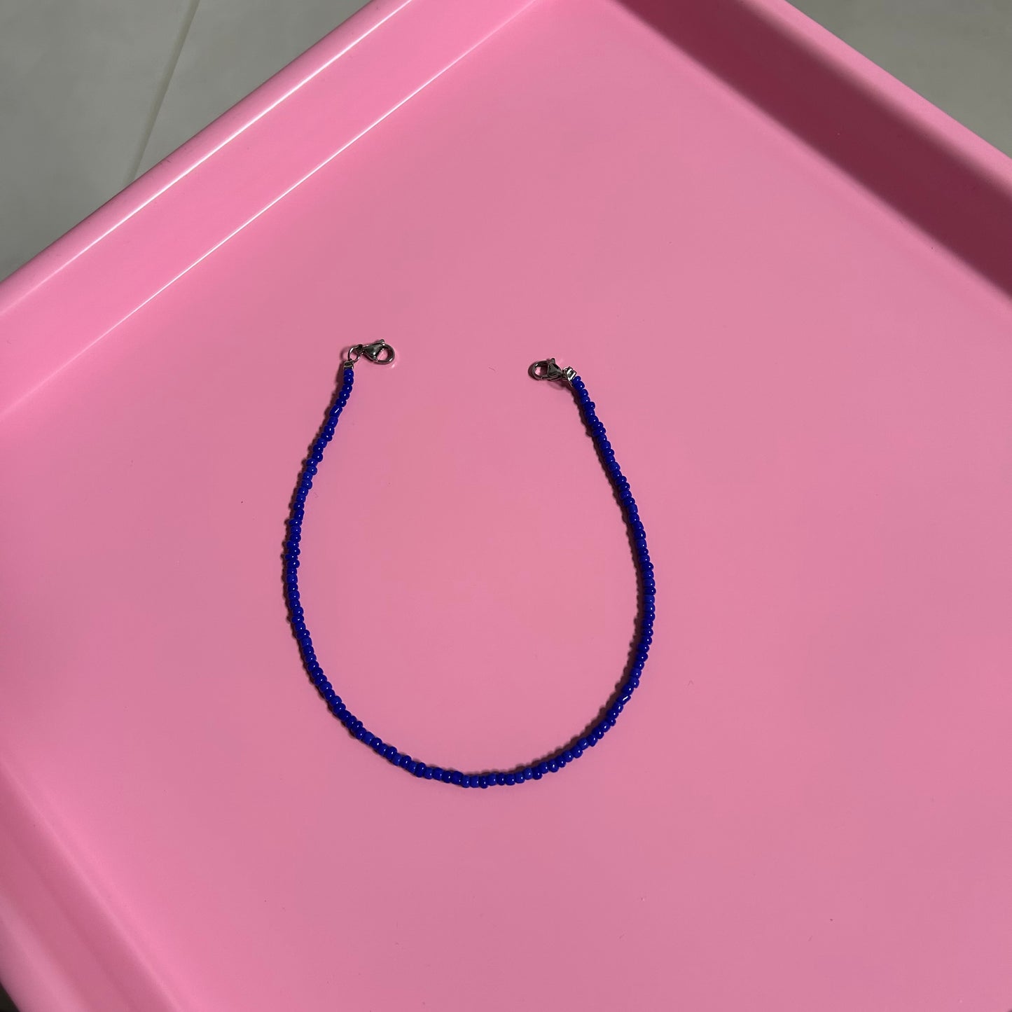 Blue beaded necklace on a pink tray