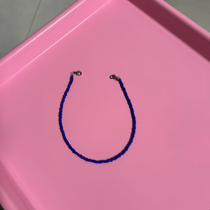 Blue beaded necklace on a pink tray
