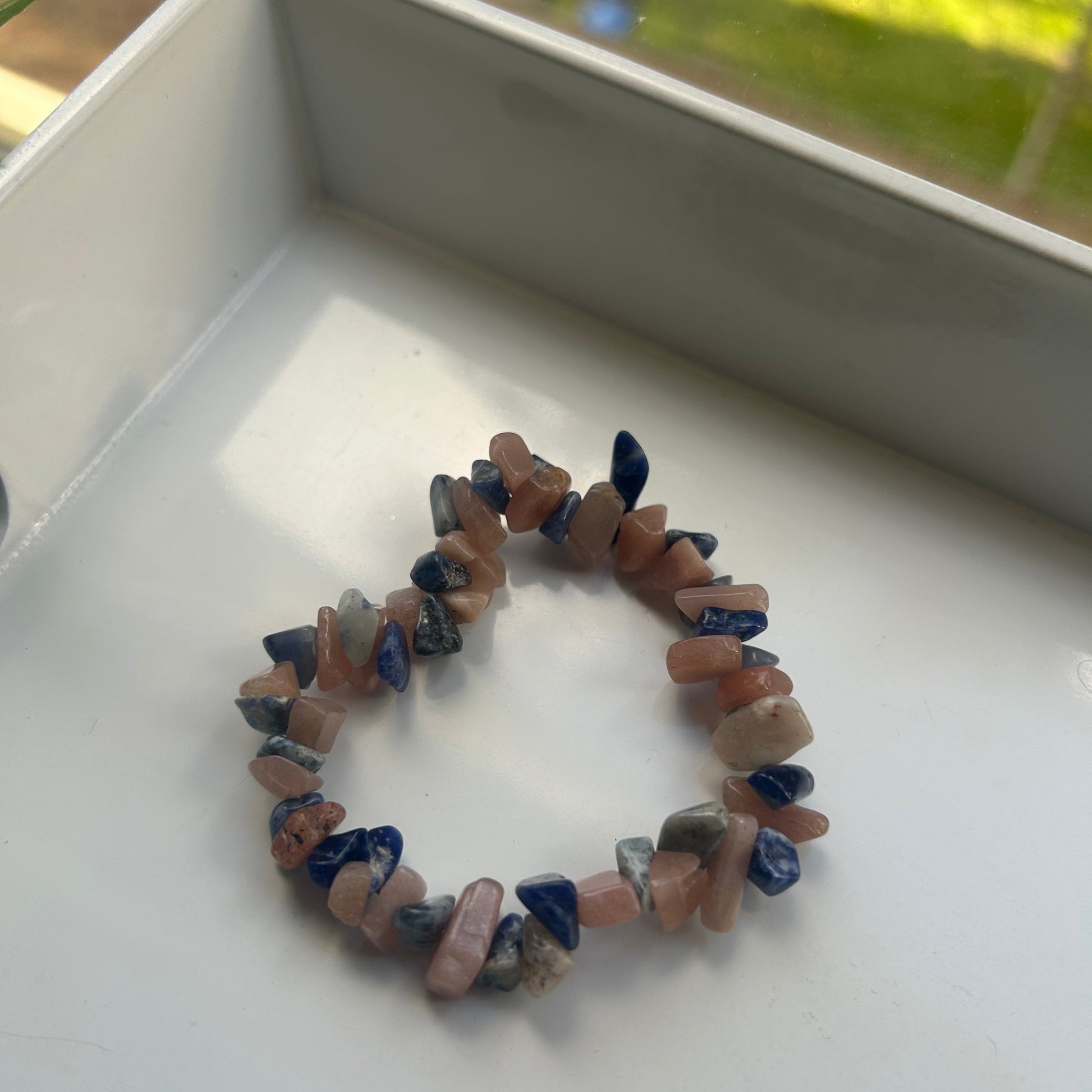 Stones bracelet on a white surface with blurred green background