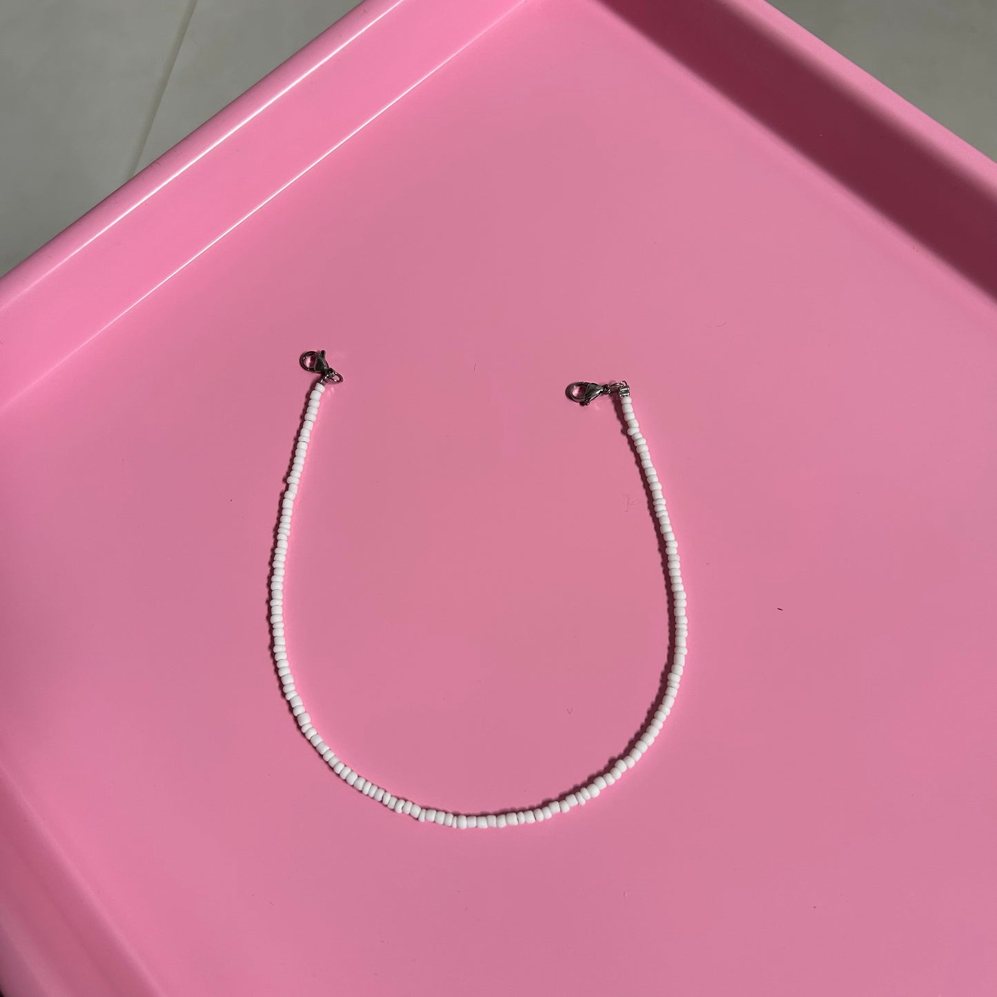 Necklace with small beads on a pink surface